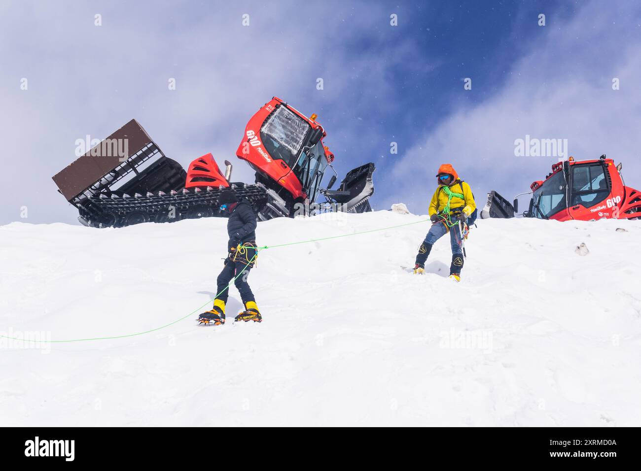 Elbrus, Russie - 01 août 2024 : les alpinistes pratiquent leurs compétences d'escalade sur une pente enneigée avec des chats à neige en arrière-plan Banque D'Images