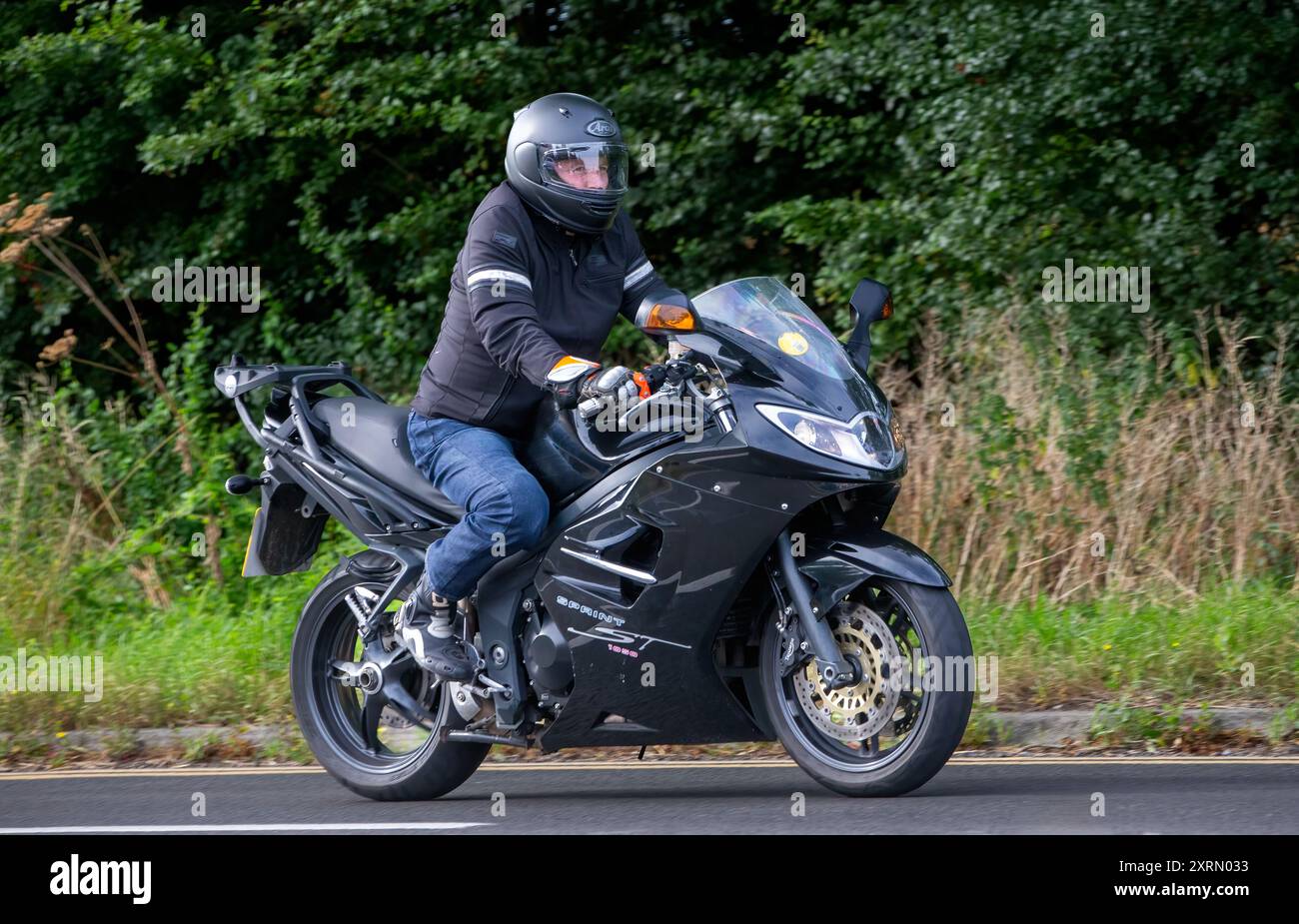 Potterspury, Northants, UK - 11 août 2024 : homme conduisant une moto Triumph Sprint ST 1050 noire voyageant sur une route britannique Banque D'Images