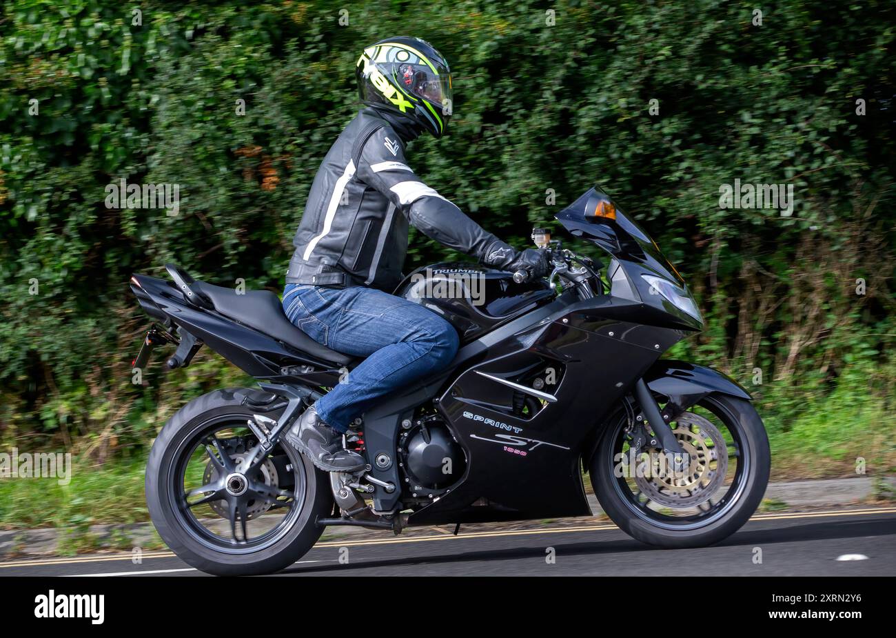 Potterspury, Northants, UK - 11 août 2024 : homme conduisant une moto Triumph Sprint ST 1050 noire voyageant sur une route britannique Banque D'Images