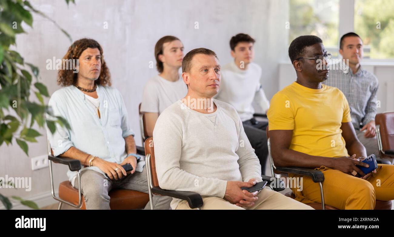 Étudiant adulte de sexe masculin écoutant la conférence avec un groupe d'hommes Banque D'Images