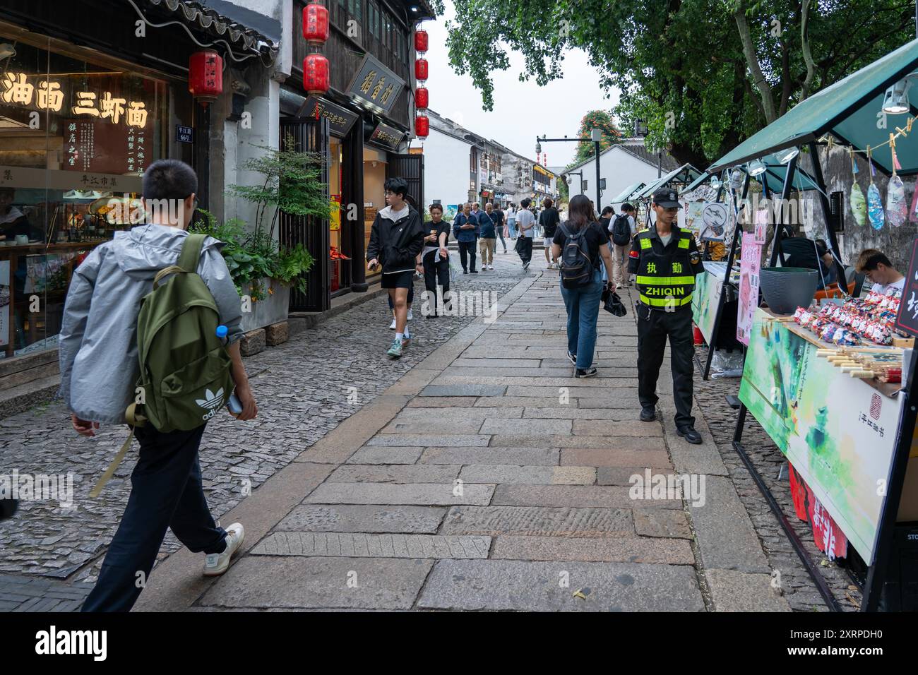 Suzhou, Chine - 11 juin 2024 : Une rue pavée bordée de magasins et de vendeurs à Suzhou, Chine. Banque D'Images