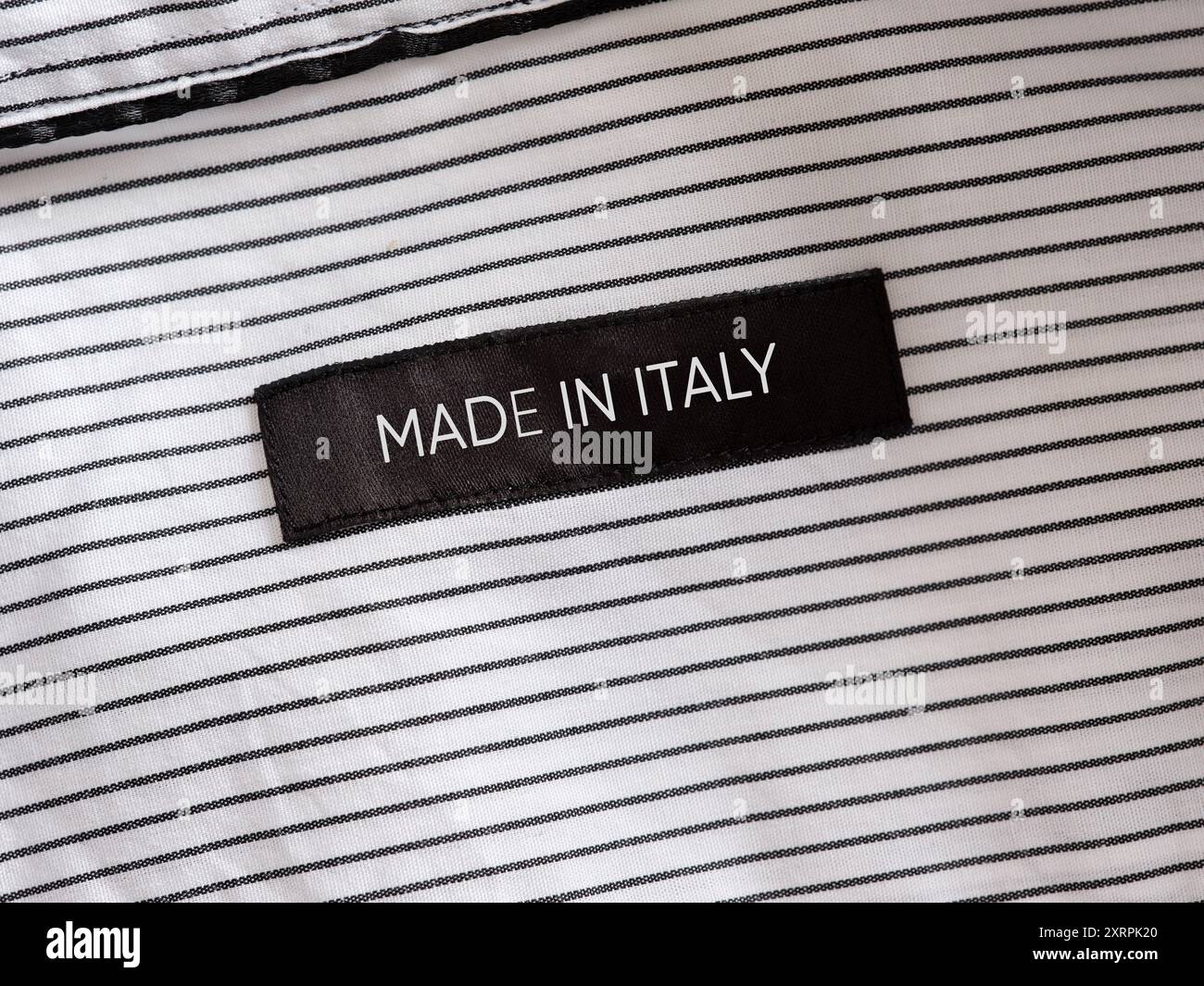 Étiquette de vêtements noirs montrant Made in Italy sur une chemise rayée, concept pour le savoir-faire italien et l'industrie de la mode Banque D'Images