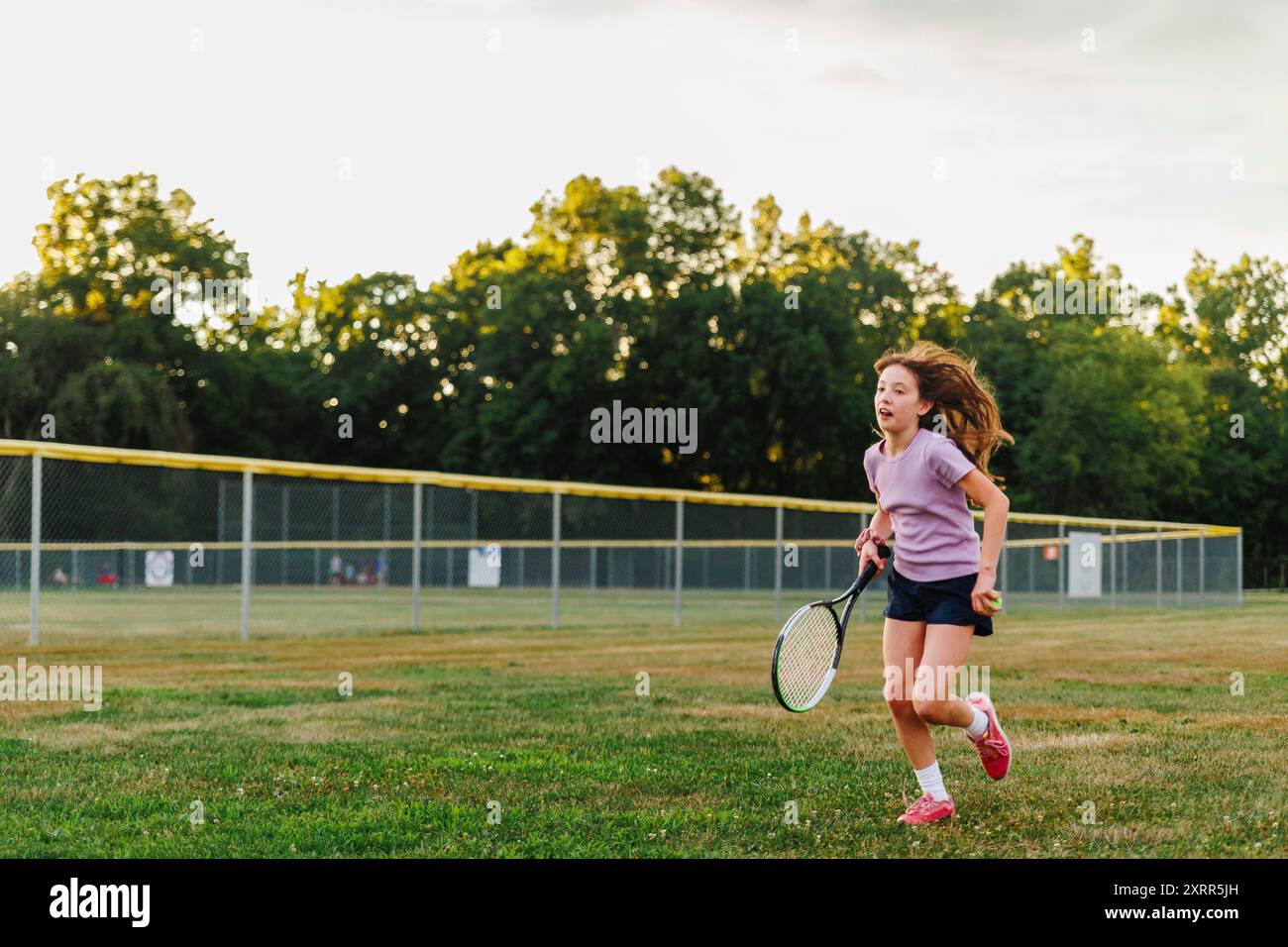 Une fille court à travers le terrain avec une raquette de tennis Banque D'Images