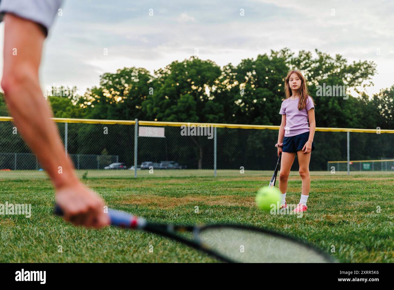 Une fille jouant au tennis avec son père sur le terrain Banque D'Images