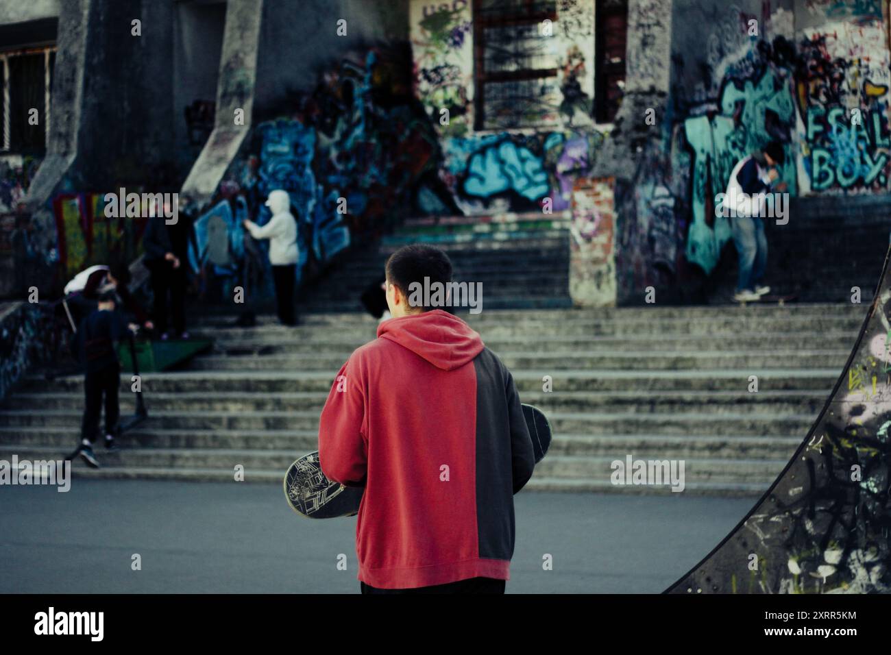 Skateboarder dans un skatepark urbain avec graffiti en arrière-plan. Banque D'Images