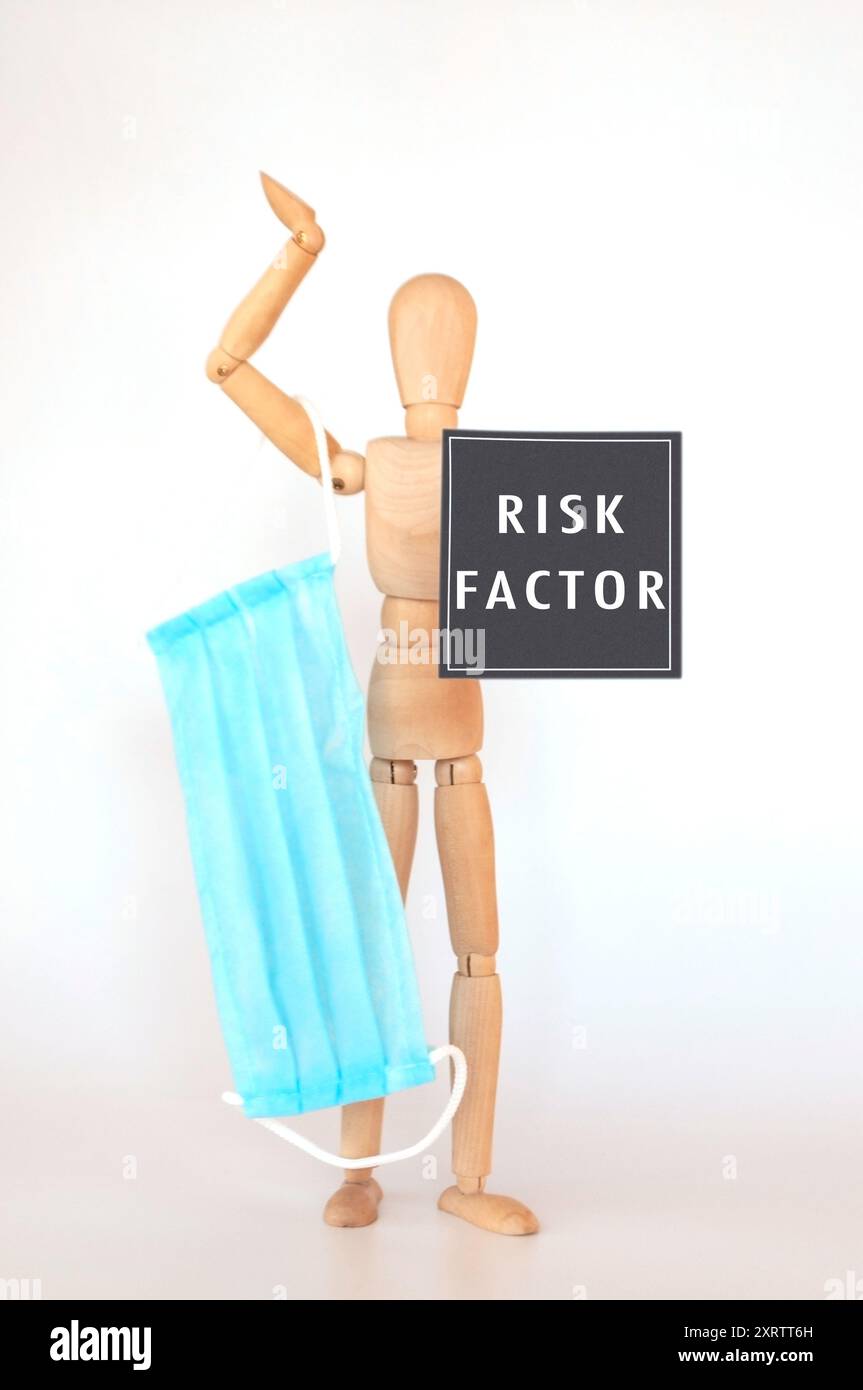 Un homme tenant un masque bleu avec les mots Risk factor écrits en dessous de lui. Concept de prudence et de sensibilisation aux risques potentiels associés à WIT Banque D'Images