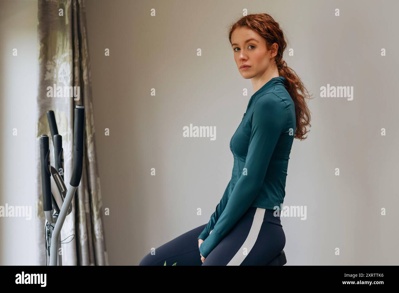 Jeune femme s'entraînant à la maison à l'aide d'un vélo elliptique. Lifestyle People Banque D'Images