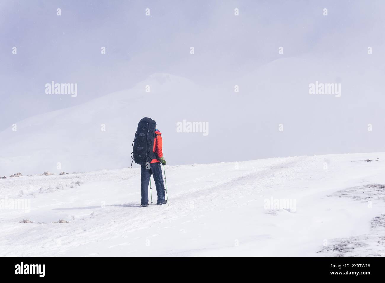 grimpeur grimpe un sommet de montagne enneigé Banque D'Images