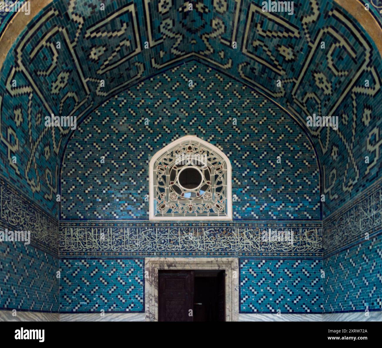 Intérieur de mosquée carrelé avec motifs géométriques et calligraphie arabe avec une fenêtre décorative voûtée Banque D'Images