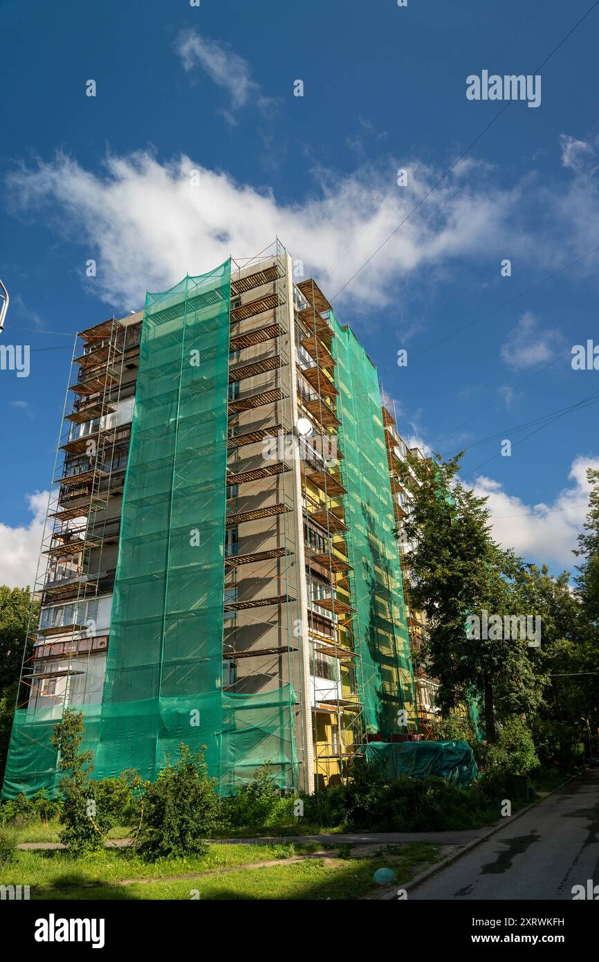 Un grand bâtiment est en cours de rénovation avec des filets verts couvrant ses côtés. Banque D'Images