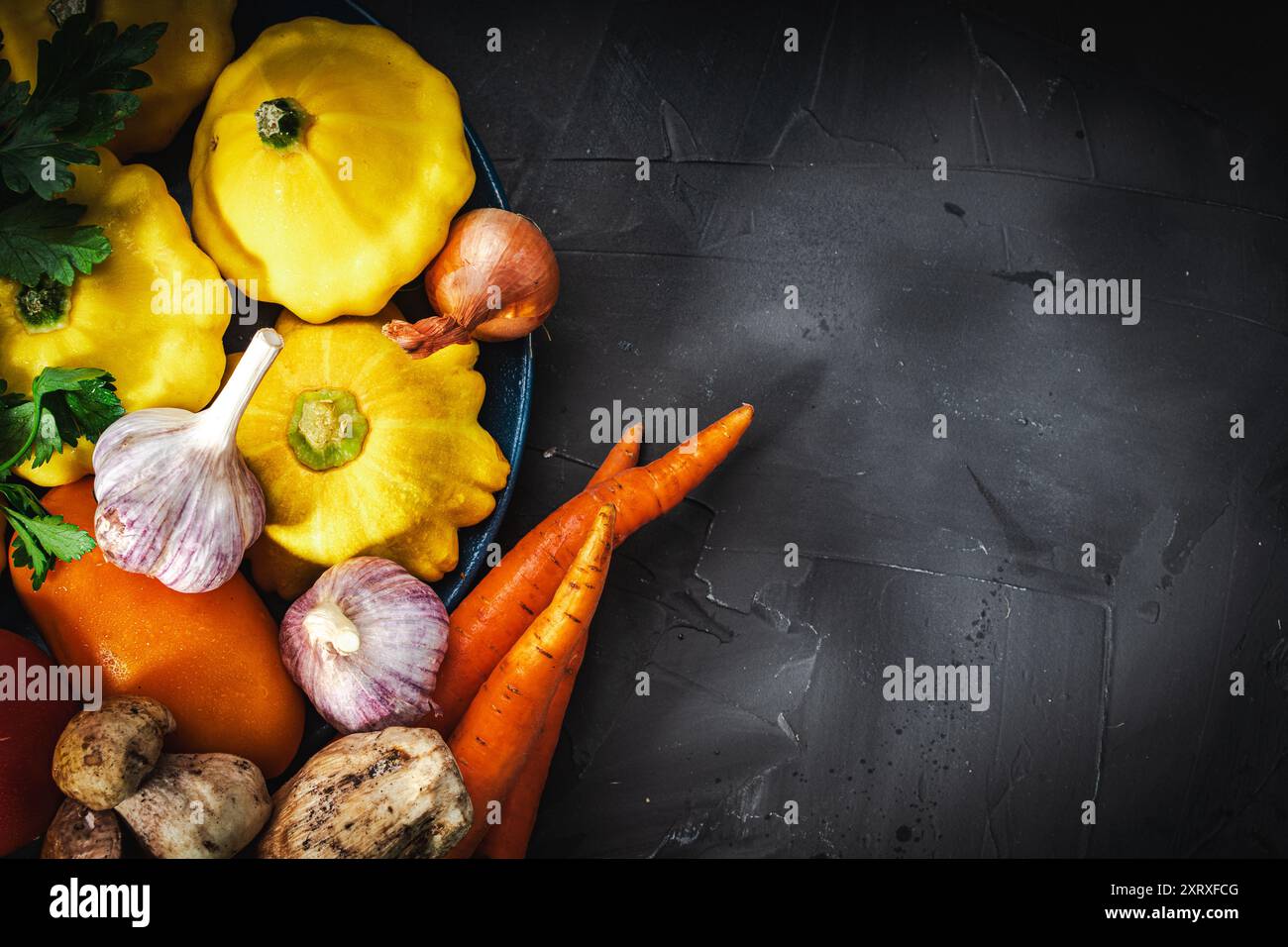 Légumes et champignons d'automne et d'été sur fond noir. Petites citrouilles jaunes, carottes, tomates et concombres, ail, oignons. Légumes de saison Banque D'Images