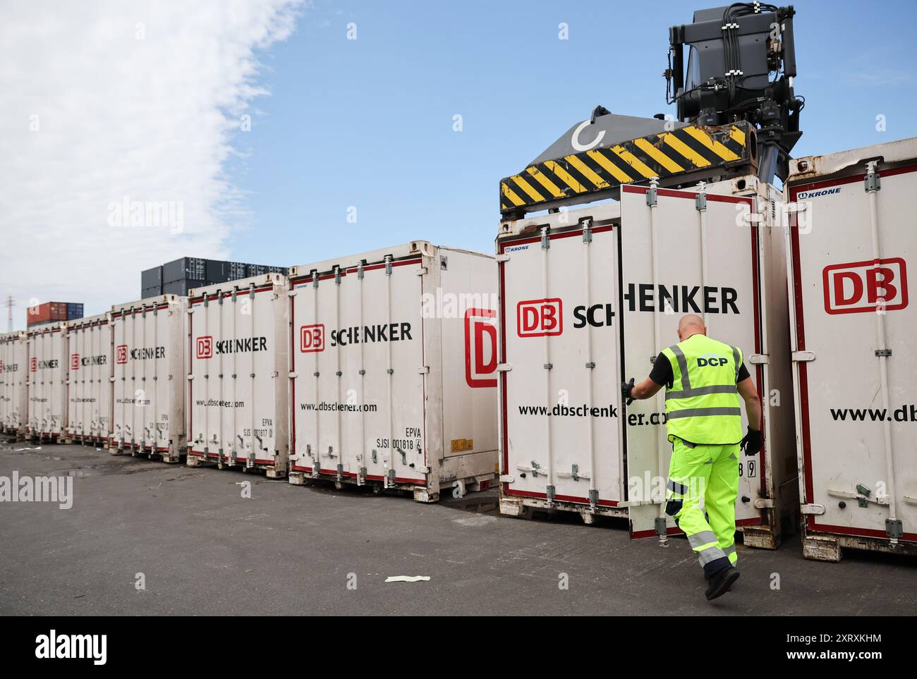 Hambourg, Allemagne. 08 août 2024. Un employé ferme un conteneur avec le logo de la société au DB Schenker Logistics Center Port de Hambourg chez DCP Dettmer Container Packing GmbH dans le port de Hambourg. Crédit : Christian Charisius/dpa/Alamy Live News Banque D'Images