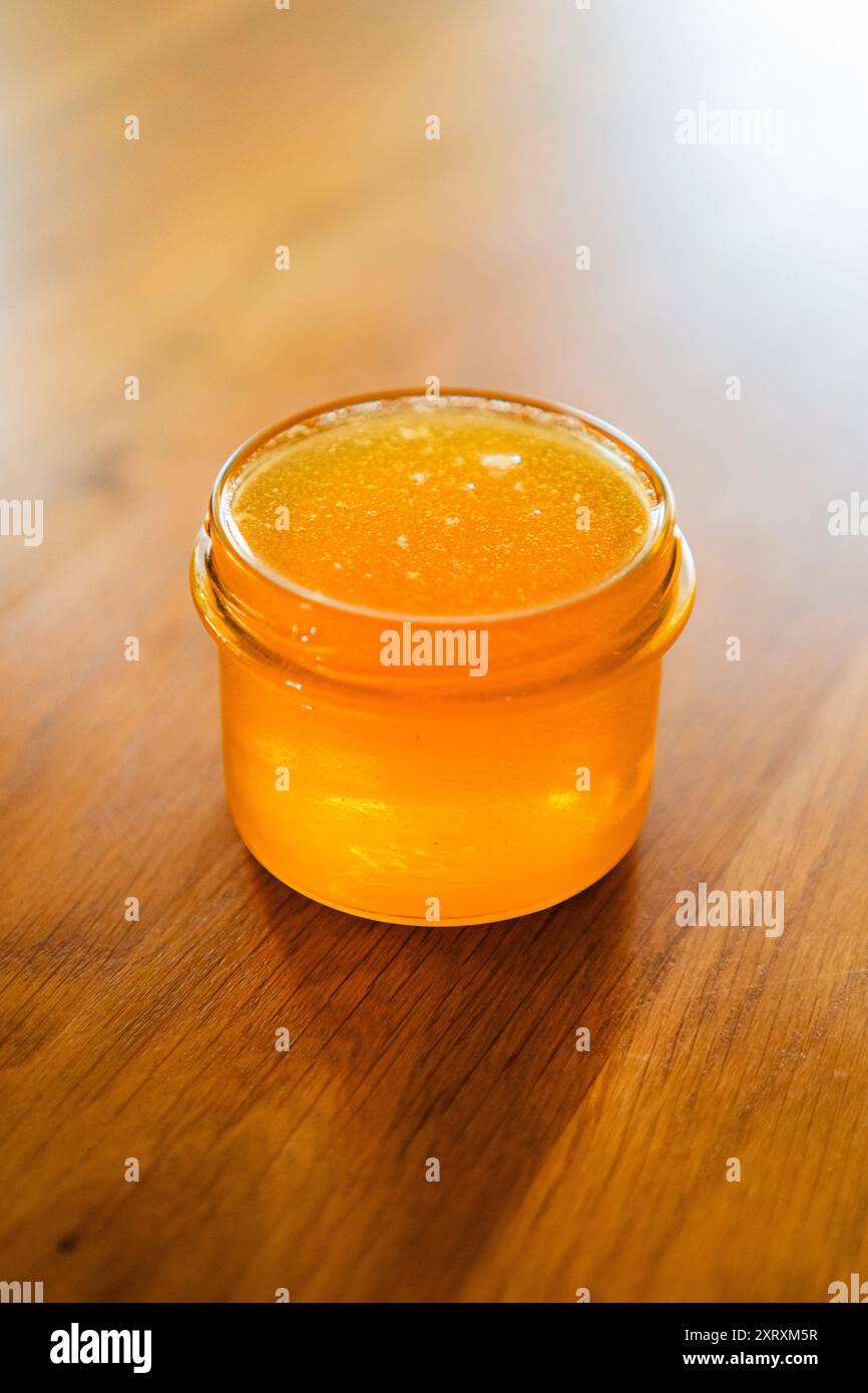 Pot de miel avec délicieux miel d'abeille dorée debout sur une table en bois Banque D'Images