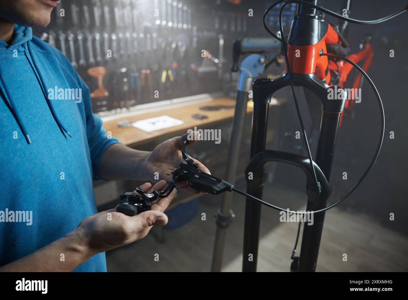 Mécanicien masculin engagé dans l'installation du système de freinage au garage de bicyclette Banque D'Images