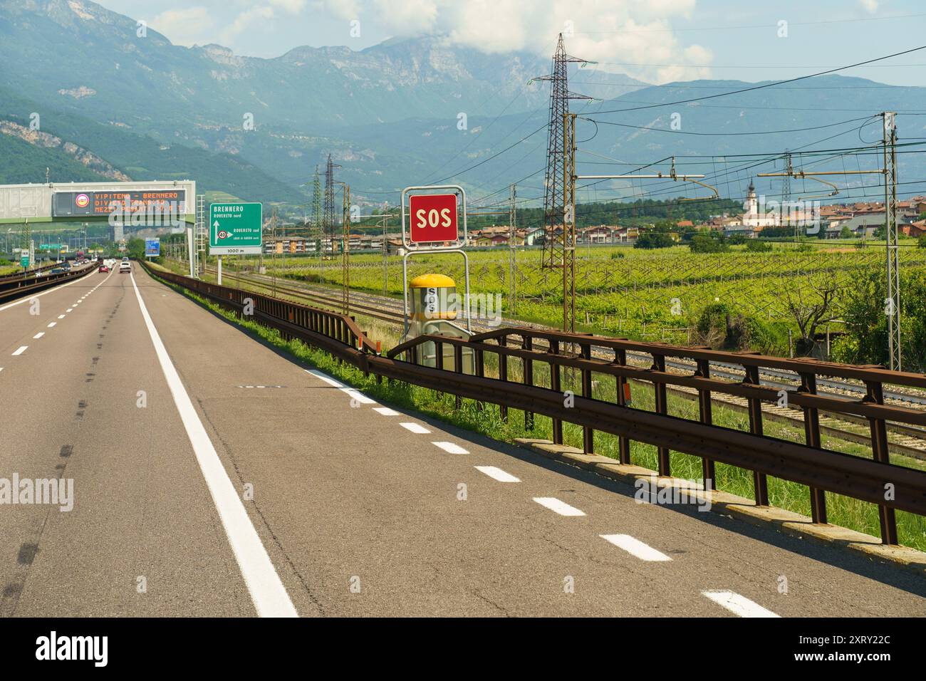 Une autoroute tranquille longe des vignobles luxuriants, avec un panneau SOS rouge vif se démarquant du paysage pittoresque. Banque D'Images
