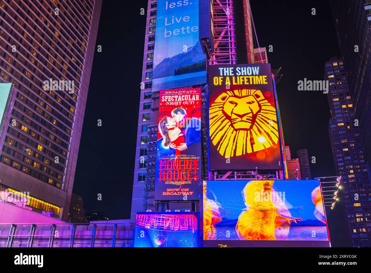 Vue nocturne sur Broadway à Manhattan, avec gratte-ciel et panneaux lumineux annonçant les comédies musicales « Moulin Rouge » et « The Show of a Life Time ». Banque D'Images