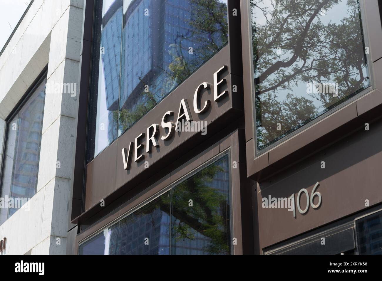 Léger coup d'œil vers le ciel à la façade du bâtiment et au signe de Versace, un magasin de vêtements, situé au 106 Yorkville Avenue dans le centre-ville de Toronto, Canada Banque D'Images