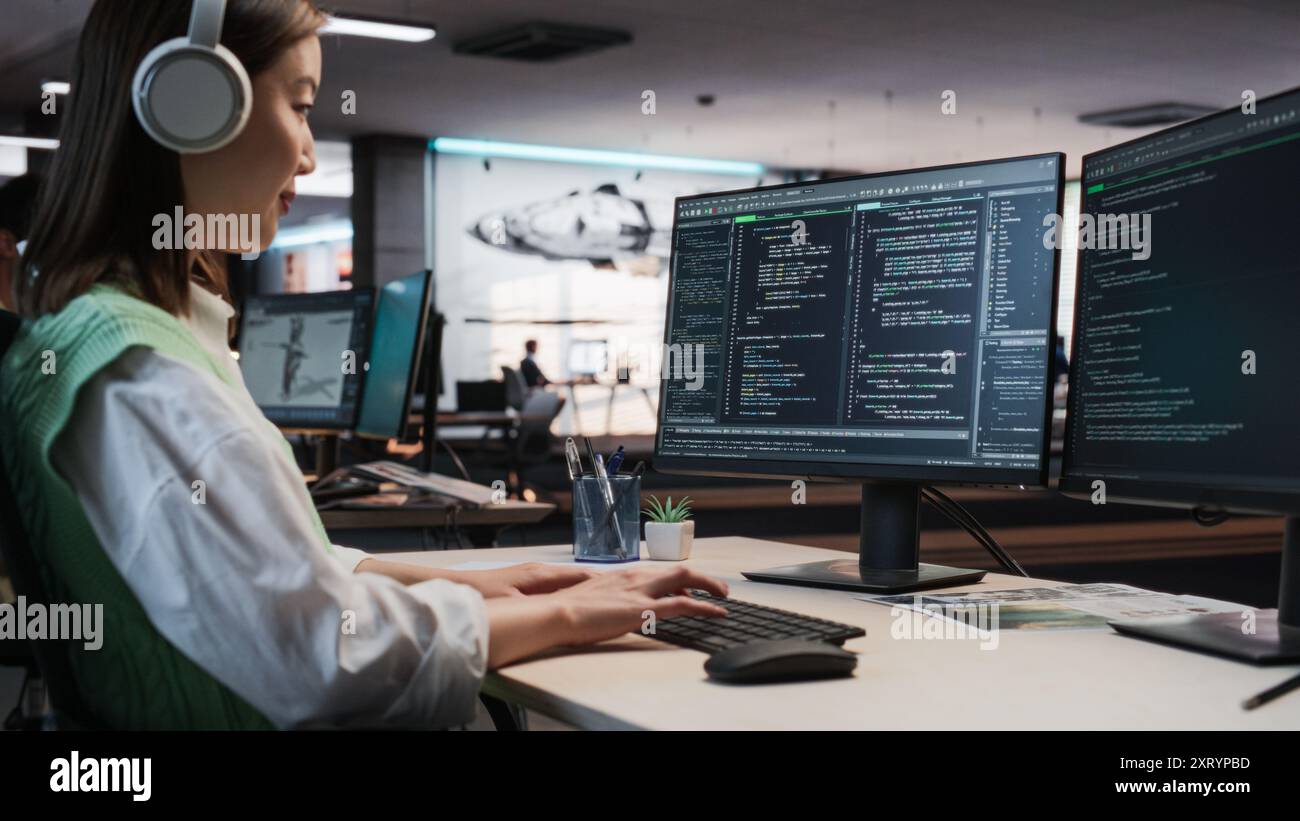 Programmeur de jeu asiatique féminin codage sur ordinateur de bureau dans Game Development Studio diverse Office. Focused Woman écrit des lignes de code. Ingénieur de gameplay du nouveau jeu vidéo de survie immersif 3D Working Banque D'Images