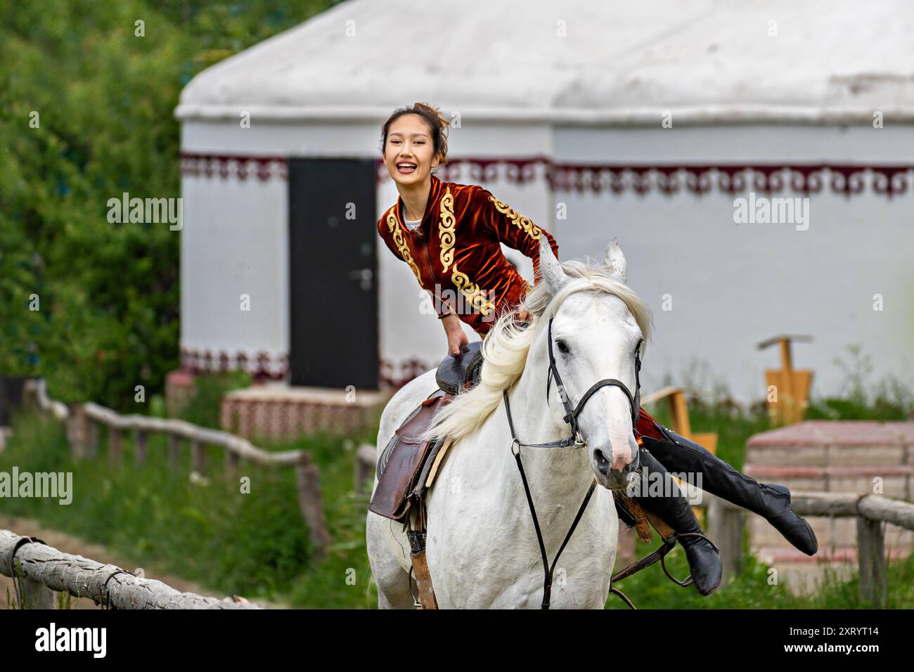 Femme nomade vêtue d'une robe locale faisant des acrobaties à cheval à Almaty, Kazakhstan Banque D'Images