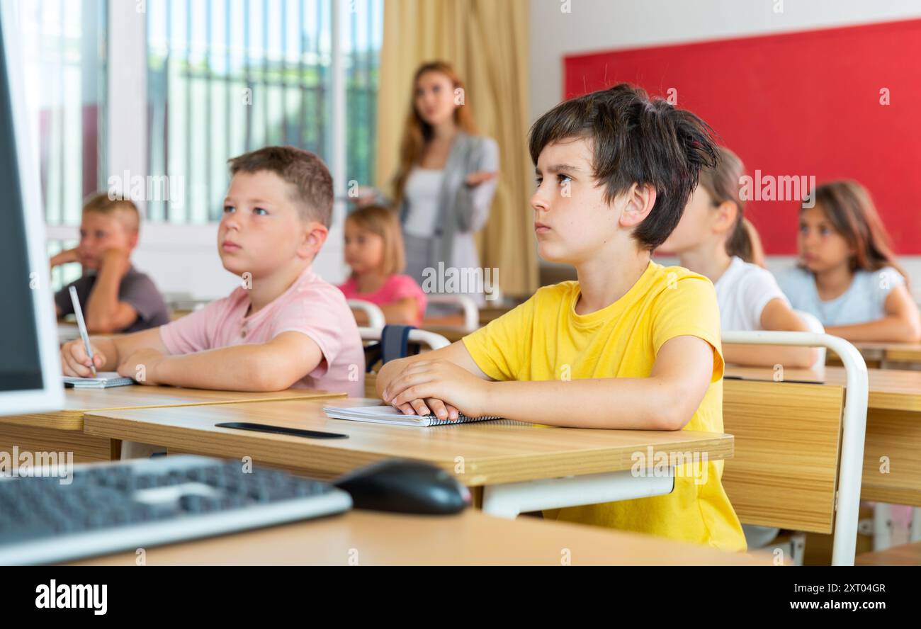 Jeune garçon diligent étudiant avec des camarades de classe à l'école Banque D'Images