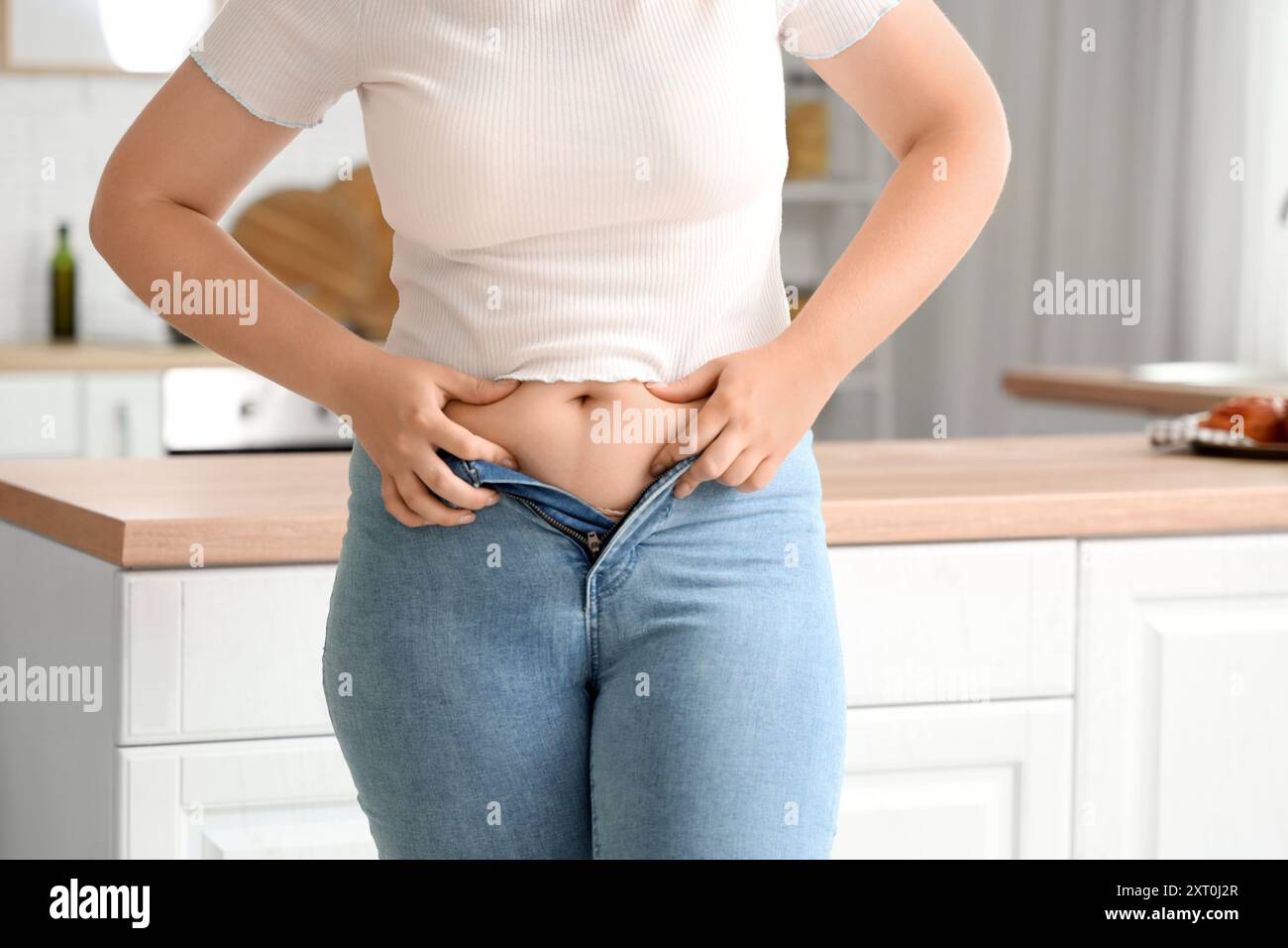 Jeune femme en Jean serré à la maison, gros plan. Concept de gain de poids Banque D'Images