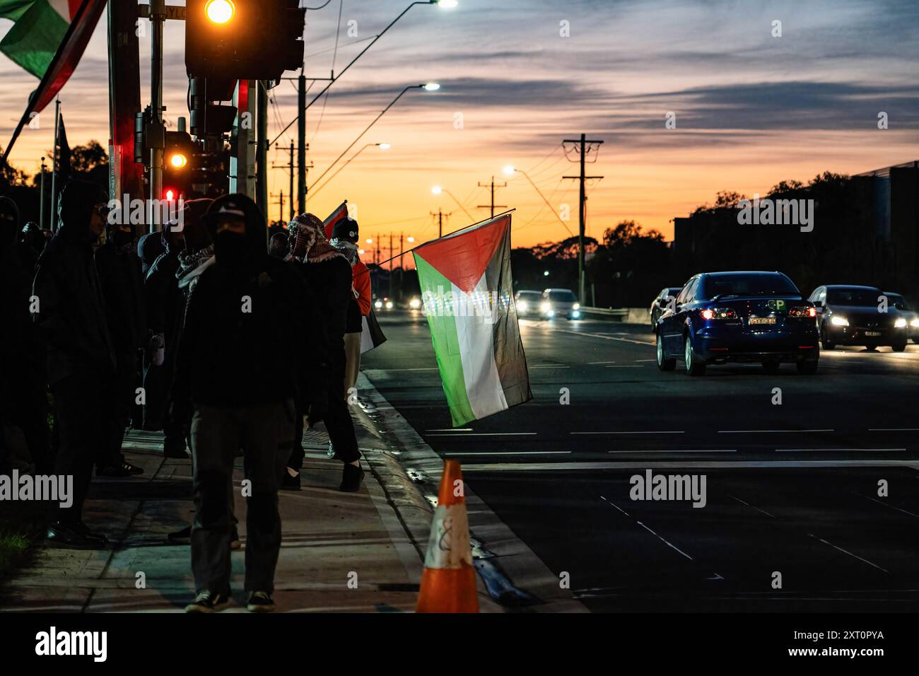 Melbourne, Australie. 13 août 2024. Les manifestants se tenant sur le côté de la route agitent les drapeaux palestiniens pendant la manifestation. Les manifestants pro-Palestine se sont rassemblés pour une manifestation devant Un W. Bell à Dandenong South Melbourne, une entreprise qui fabrique des pièces pour Israël. La manifestation a duré près de 5 heures, elle a pris fin après qu'ils aient reçu un déménagement sur ordre de la police et ont été surpassés en nombre. Les travailleurs de A.W.Bell ont pu commencer leur quart de travail lorsque la police a créé une barrière contre les manifestants. Crédit : SOPA images Limited/Alamy Live News Banque D'Images