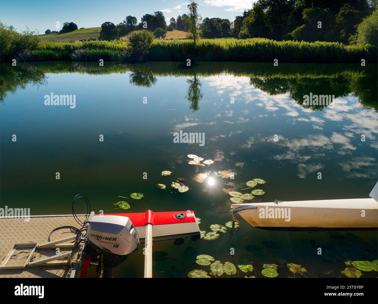 Fondé en 1921 et situé sur une belle partie de la Tamise dans l'Oxfordshire, Radley Boathouse sert Radley College et les amateurs d'aviron locaux depuis plus d'un siècle. Si vous vous tenez sur sa jetée et regardez à travers la rive nord de la rivière, vous verrez un arbre isolé et plutôt charmant, qui semble changer de caractère et d'apparence tout au long de l'année. Ici, nous le voyons par une belle et ensoleillée matinée d'été, avec les catamarans de plaisir omniprésents du hangar à bateaux au premier plan. La Croix de Malte rouge est l'emblème du club de navigation de l'université. Banque D'Images