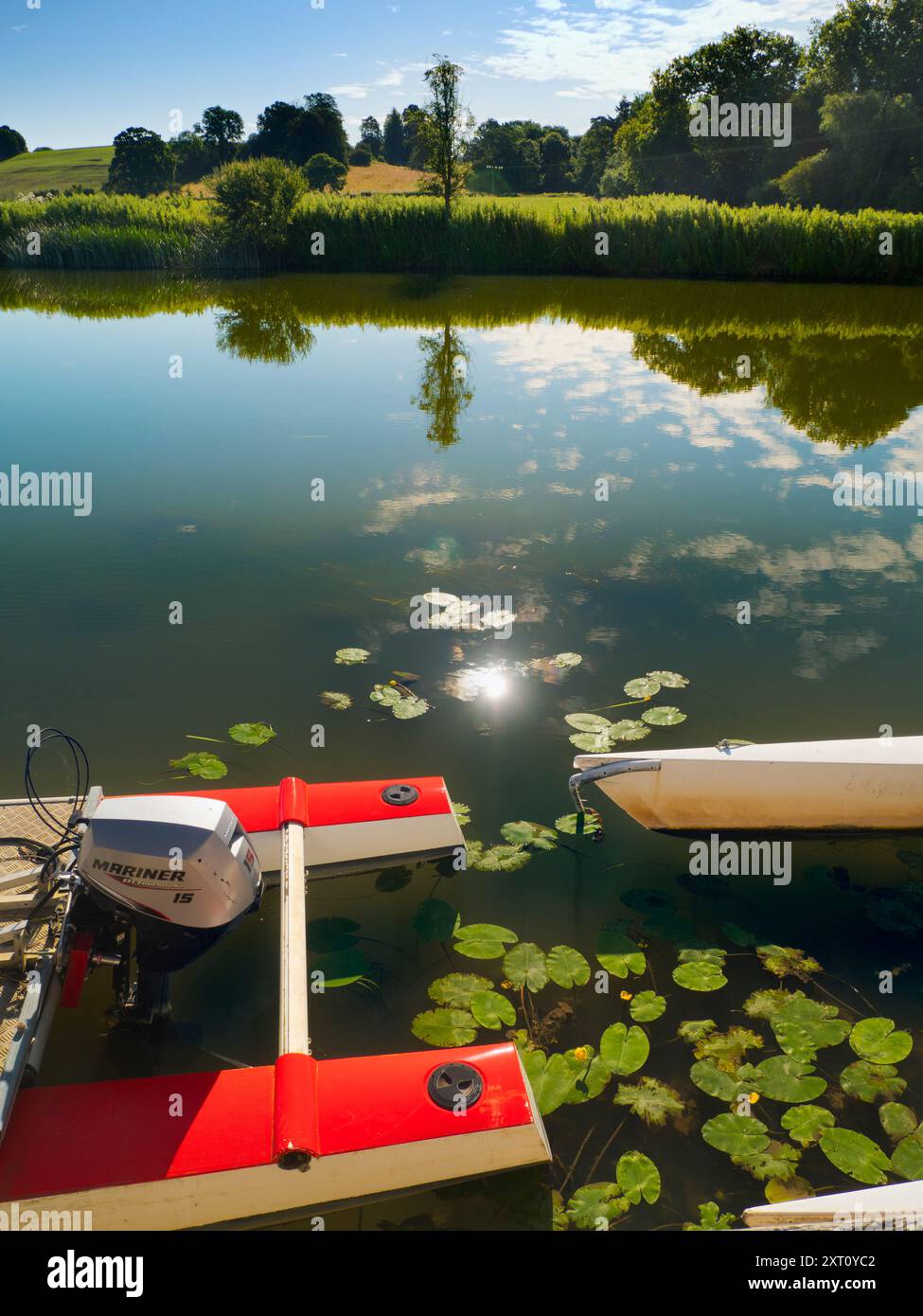 Fondé en 1921 et situé sur une belle partie de la Tamise dans l'Oxfordshire, Radley Boathouse sert Radley College et les amateurs d'aviron locaux depuis plus d'un siècle. Si vous vous tenez sur sa jetée et regardez à travers la rive nord de la rivière, vous verrez un arbre isolé et plutôt charmant, qui semble changer de caractère et d'apparence tout au long de l'année. Ici, nous le voyons par une belle et ensoleillée matinée d'été, avec les catamarans de plaisir omniprésents du hangar à bateaux au premier plan. La Croix de Malte rouge est l'emblème du club de navigation de l'université. Banque D'Images