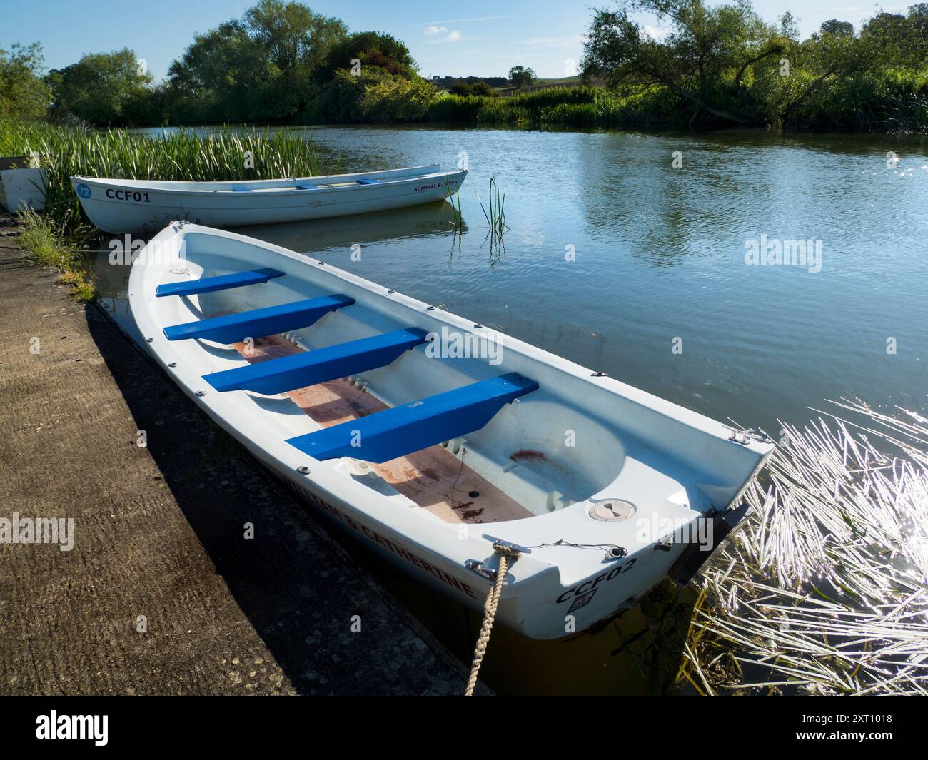 Fondé en 1921 et situé sur une belle partie de la Tamise dans l'Oxfordshire, Radley Boathouse sert Radley College et les amateurs d'aviron locaux depuis plus d'un siècle. Ici, nous voyons deux bateaux à rames amarrés par sa jetée, tôt par un beau matin d'été. Banque D'Images