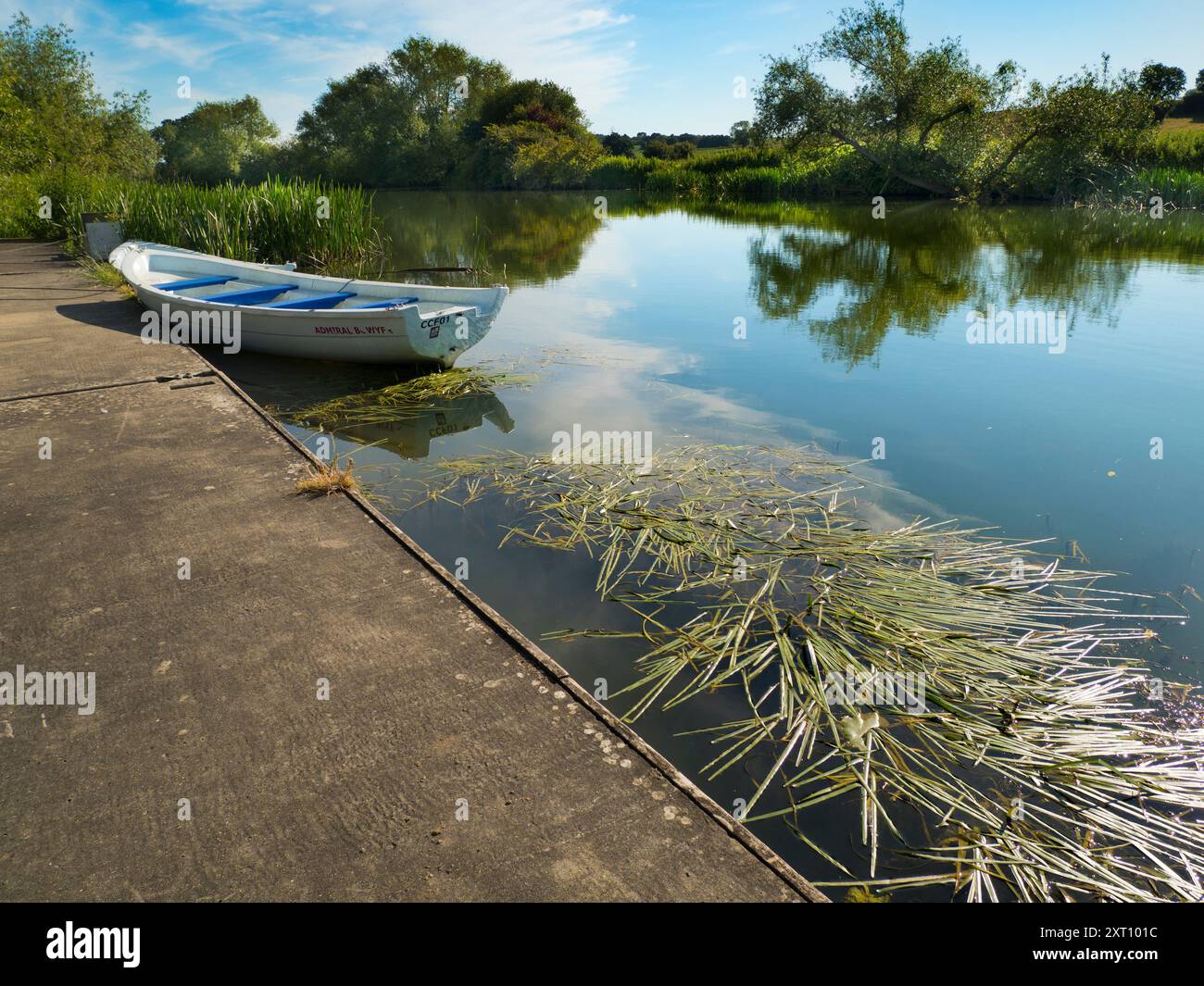 Fondé en 1921 et situé sur une belle partie de la Tamise dans l'Oxfordshire, Radley Boathouse sert Radley College et les amateurs d'aviron locaux depuis plus d'un siècle. Ici, nous voyons deux bateaux à rames amarrés par sa jetée, tôt par un beau matin d'été. Banque D'Images