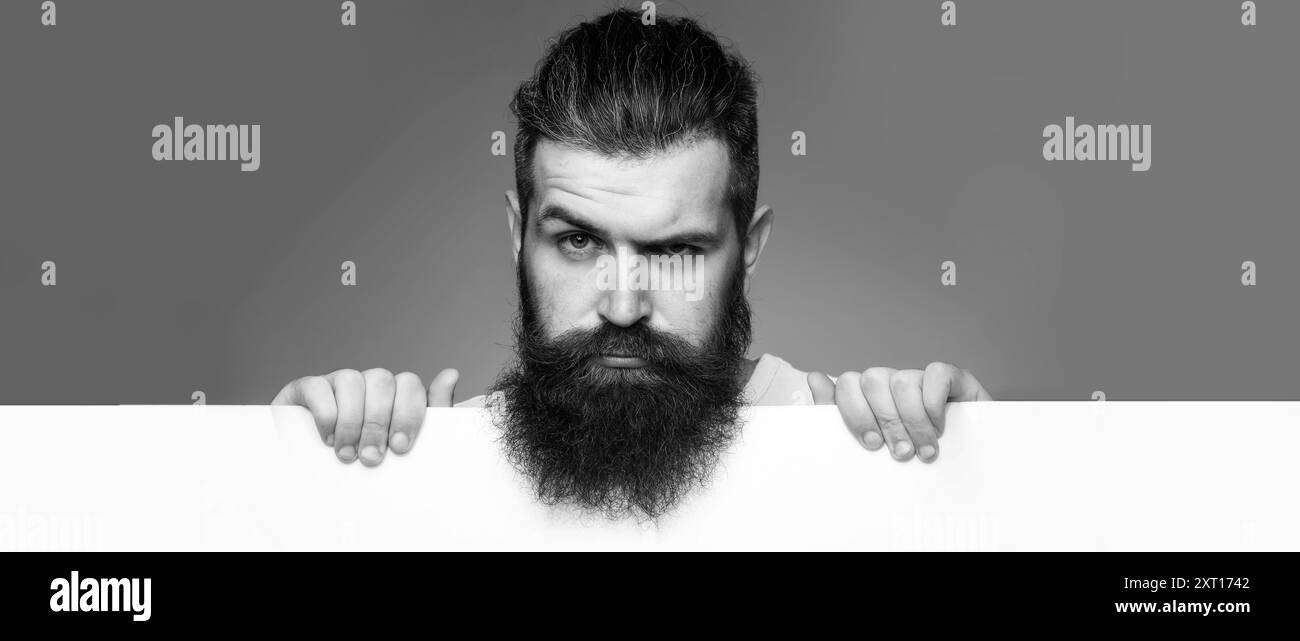 Homme de barbe avec barbe longue classique, gay barbu.Beau barbu avec une longue barbe et une moustache sur un visage sérieux avec une feuille de papier blanche Banque D'Images