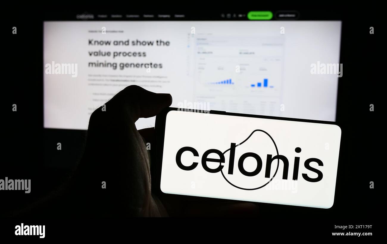 Personne tenant le téléphone portable avec le logo de la société de logiciels de traitement de données Celonis se en face de la page Web de l'entreprise. Concentrez-vous sur l'affichage du téléphone. Banque D'Images