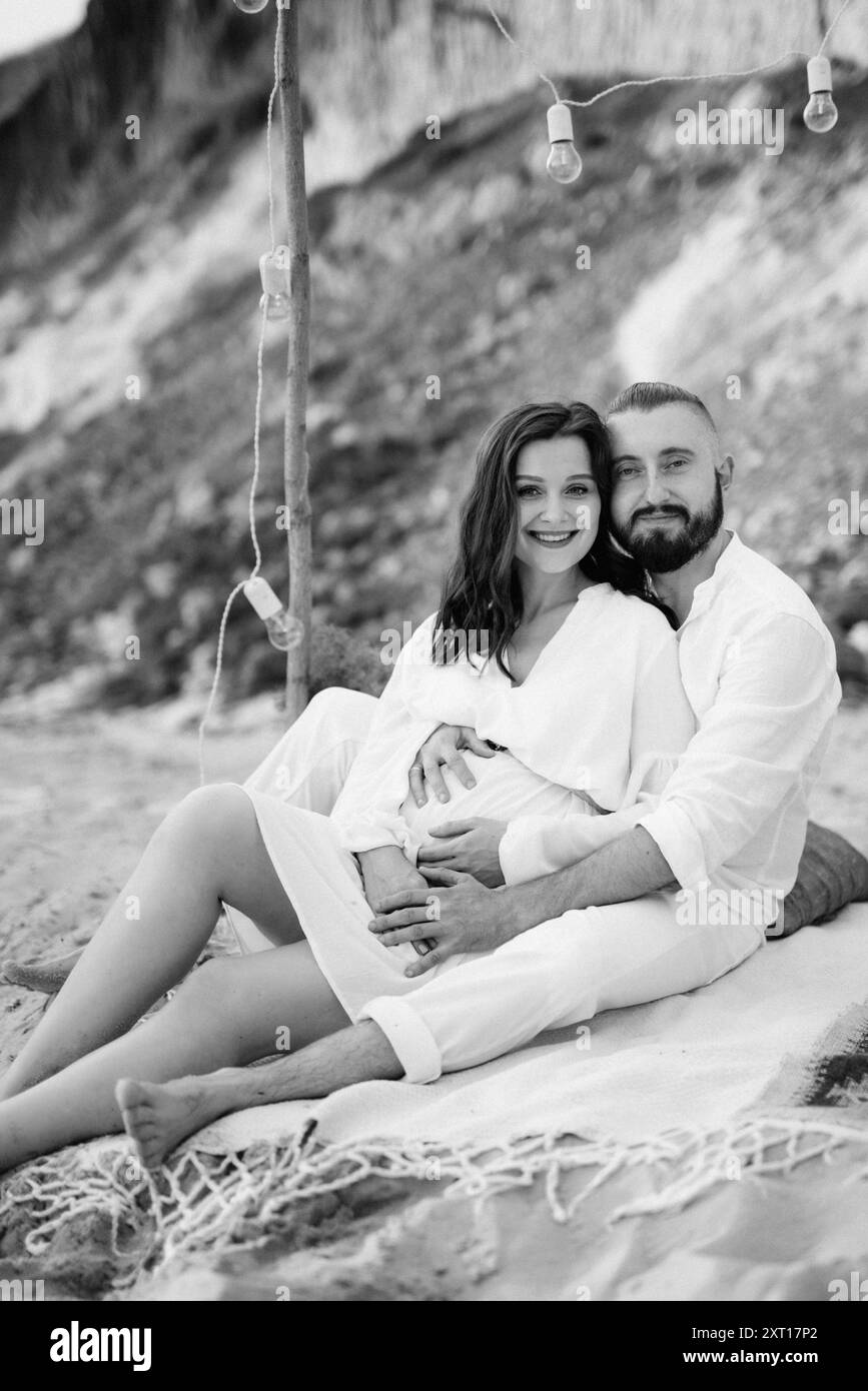 fille enceinte et petit ami sur un pique-nique au bord de la mer en vêtements blancs Banque D'Images