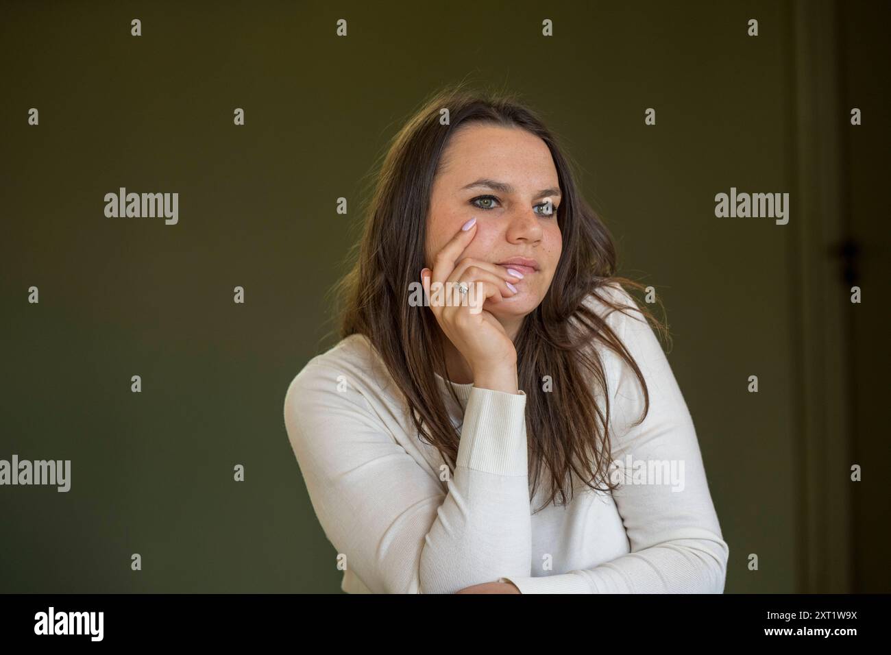 Femme en haut blanc menton reposant sur la main, profonde dans la pensée sur un fond vert. Panc05623 Copyright : xConnectxImagesx Banque D'Images