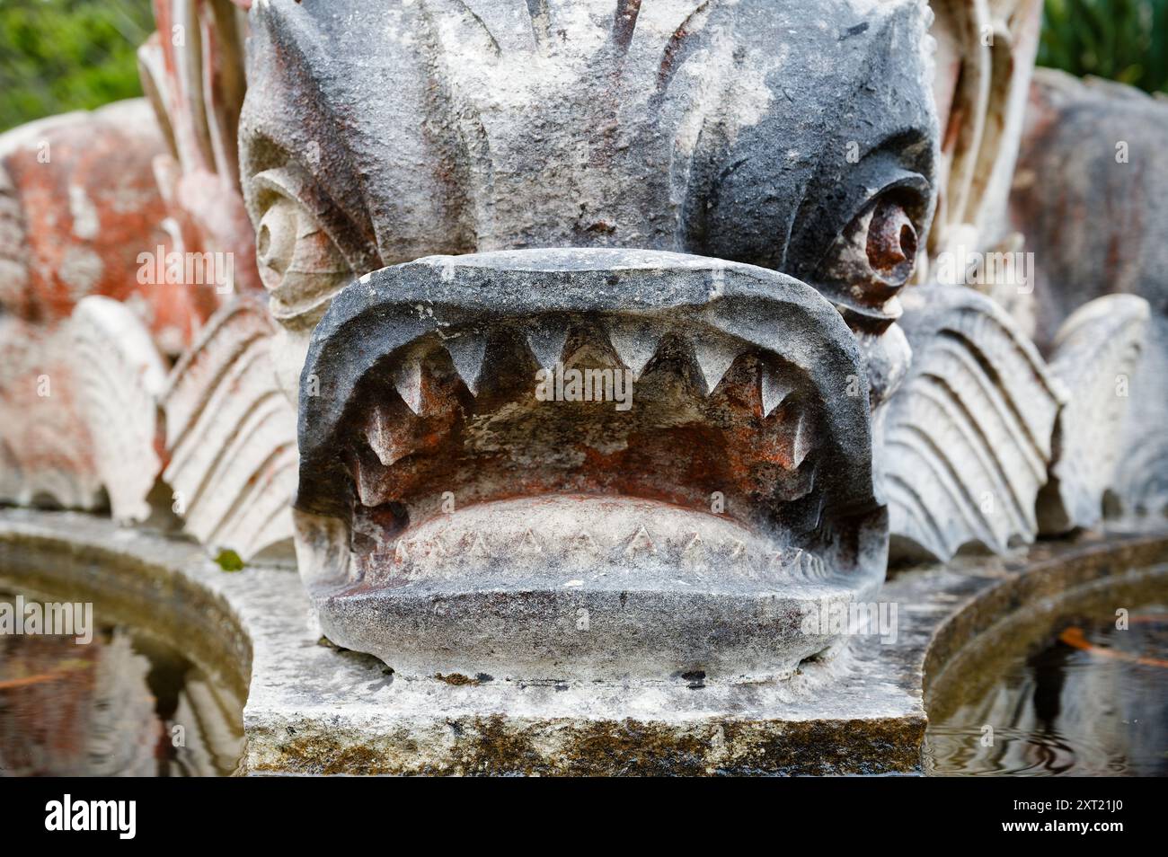 Gros plan d'une sculpture de poisson en pierre altérée, montrant des dents pointues et détaillées Banque D'Images