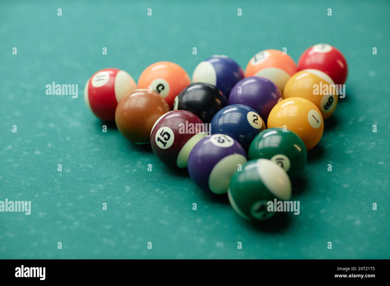 Gros plan de boules de billard colorées disposées en triangle sur une table de billard verte pour la configuration du jeu avec des numéros visibles Banque D'Images