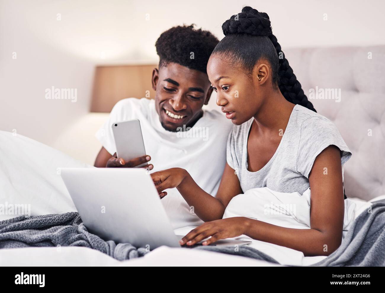 Couple, détente et discussion avec la technologie dans la chambre à coucher pour le menu en ligne, la recherche et l'idée de petit déjeuner. Homme, femme et conversation avec ordinateur portable dans l'hôtel Banque D'Images