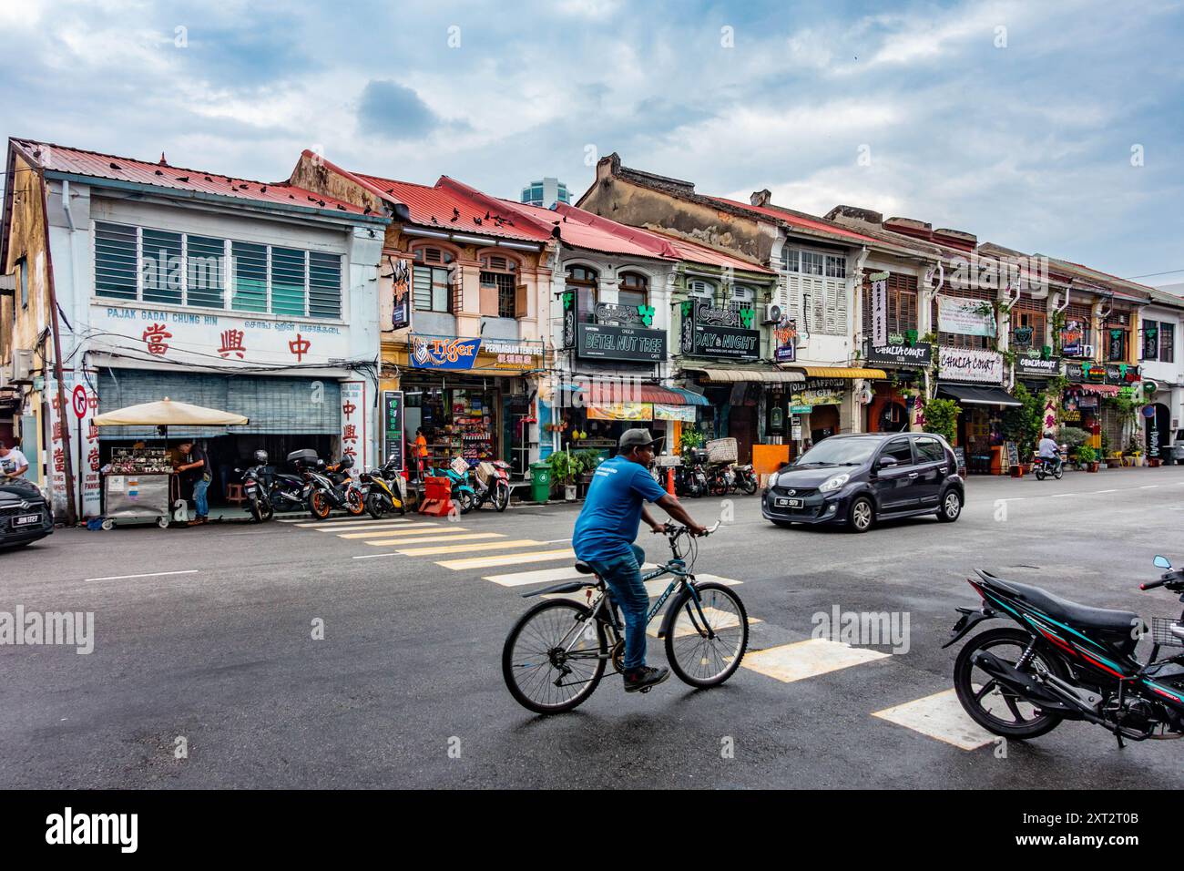 Une scène de rue animée, un cycliste chevauche un passage piétonnier qui traverse la rue Chulia à George Town, Penang, Malaisie Banque D'Images