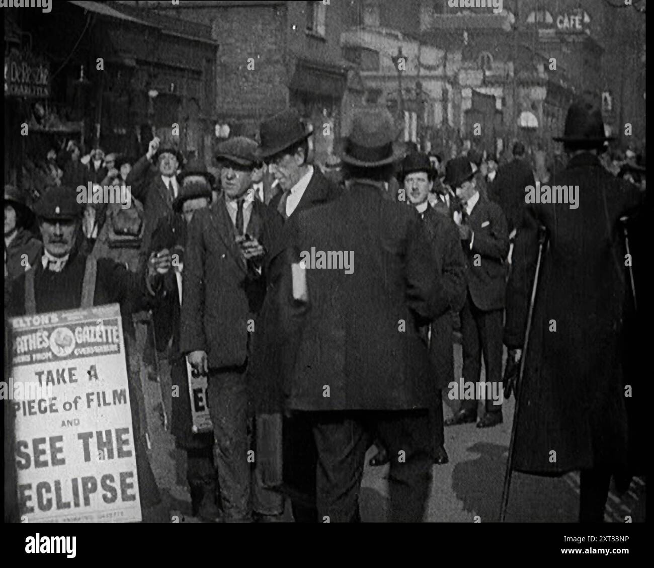 Hommes portant des planches sandwich « Pathe Gazette » distribuant des morceaux de film Polaroid à des foules avec lesquelles voir une éclipse solaire partielle, 1921. De "Time to Remember - The Time When Little Happen", 1921 (bobine 2) ; événements de 1921 - traité irlandais, cascades folles et journaux au travail. Banque D'Images