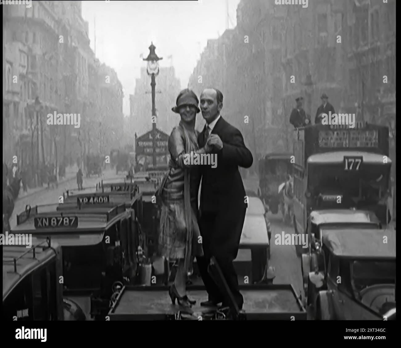 Un couple dansant le Charleston sur le dessus d'une voiture conduisant dans une rue de Londres, 1926. De "Time to Remember 1926 - Short Sharp Shower" ( Reel 4) ; documentaire sur 1926 - grève générale, politique internationale, danse, météo et exploits record. Banque D'Images