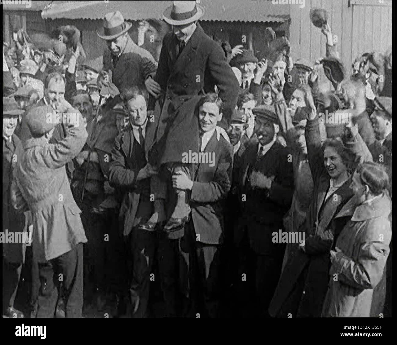 Aviateurs Capitaine Sir Ross Macpherson Smith et Lieutenant Sir Keith Macpherson Smith levés sur les épaules d'une foule, 1921. De "Time to Remember - The Time When Little Happen", 1921 (bobine 2) ; événements de 1921 - traité irlandais, cascades folles et journaux au travail. Banque D'Images