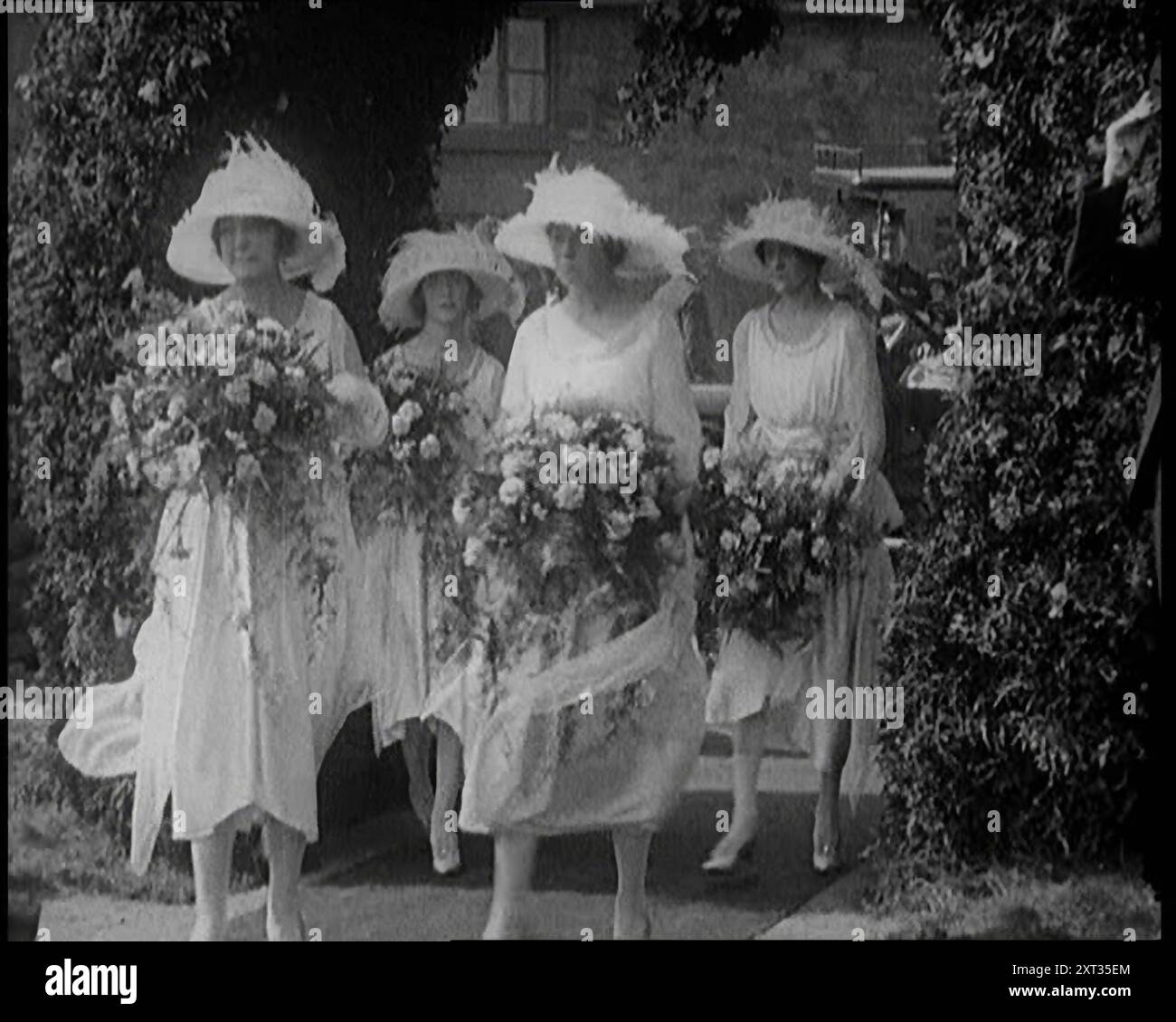 Demoiselles d'honneur britanniques marchant à travers une arche fleurie, Holding Flowers, 1921. De "Time to Remember - The Time When Little Happen", 1921 (bobine 1) ; événements de 1921 - traité irlandais, cascades folles et journaux au travail. Banque D'Images