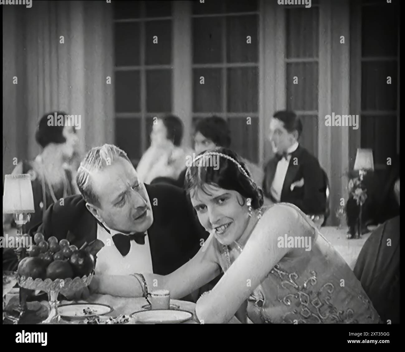 Scène du film 'Champagne' : deux acteurs assis à une table dans une boîte de nuit, années 1920 De "Time to Remember - came the Dawn", 1925 (Reel 3) ; aperçu de l'industrie cinématographique britannique des années 1920 - extraits de grands films muets et de nouvelles. Banque D'Images