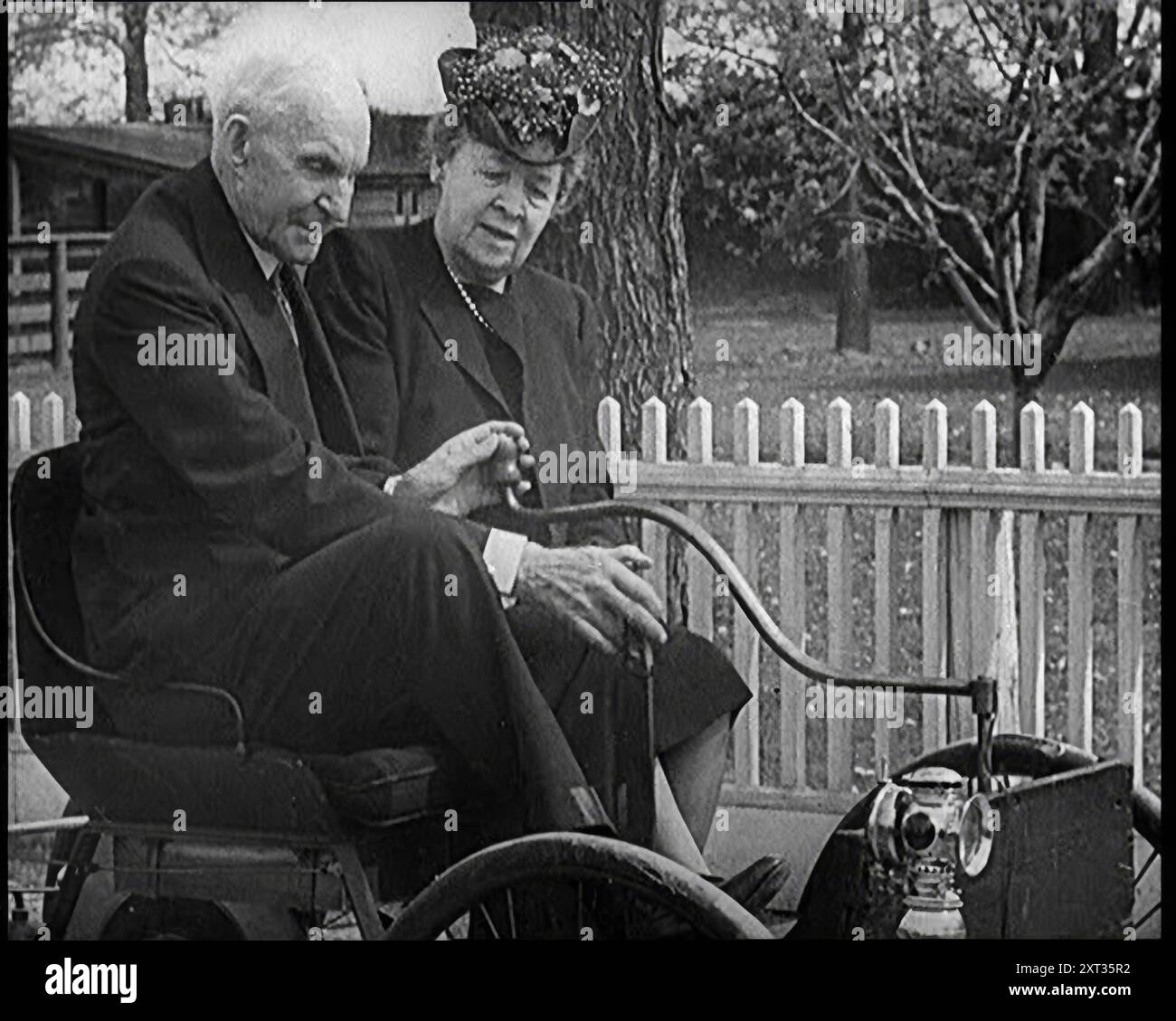 Henry et Clara Ford assis dans une vieille voiture, 1921. De "Time to Remember - The Time When Little Happen", 1921 (bobine 3) ; événements de 1921 - traité irlandais, cascades folles et journaux au travail. Banque D'Images