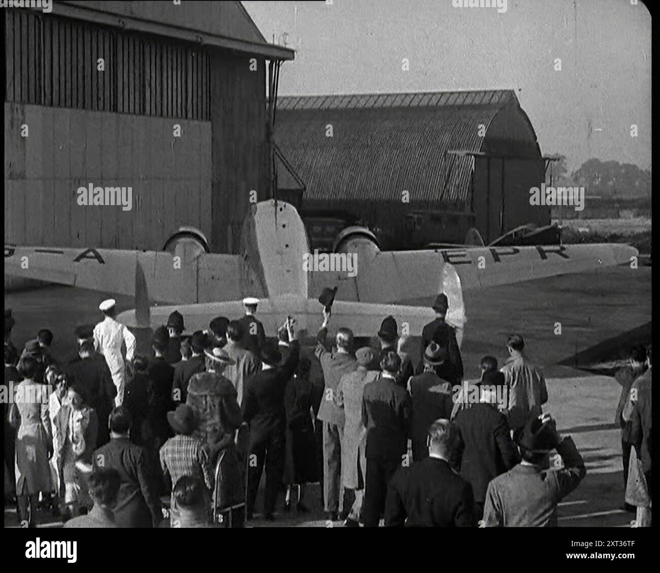 Une petite foule à l'aérodrome de Heston acclamant l'avion Lockheed en mouvement transportant le premier ministre britannique Neville Chamberlain lors de son voyage à Munich, en 1938. De "Time to Remember - Wind Up week", 1938 (bobine 1) ; film documentaire sur 1938 - les gens prennent conscience de la menace croissante de la guerre. Banque D'Images
