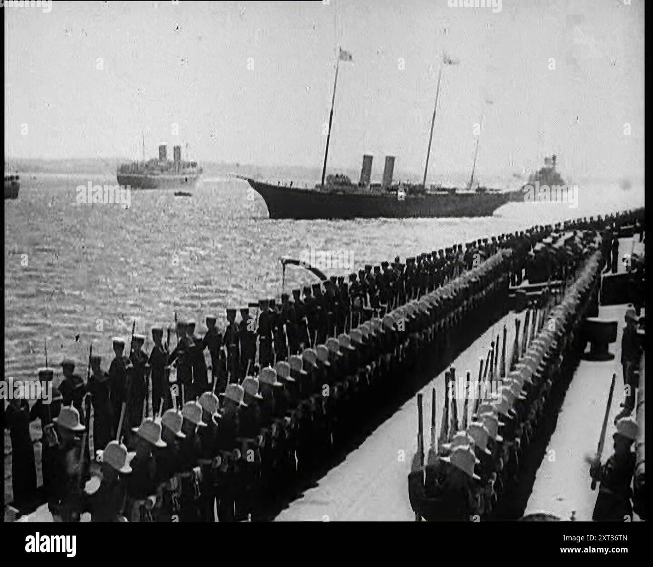 Les marins britanniques debout à l'attention alors que les navires de guerre britanniques naviguent passé, 1935. De "Time to Remember - Some People in the Thirties", années 1930 (bobine 4) ; film documentaire sur les années 1930, mettant l'accent sur des personnages célèbres de l'époque. Banque D'Images