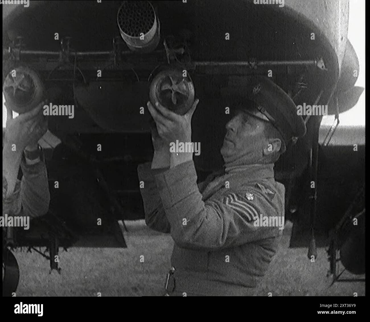 Officiers britanniques mâles montant des bombes dans un avion de chasse, années 1920 De "Time to Remember - Fast and Far in the Twenties", 1927 (Reel 2 - Record B) ; un regard sur l'obsession de la vitesse et du voyage à la fin des années 1920 Banque D'Images