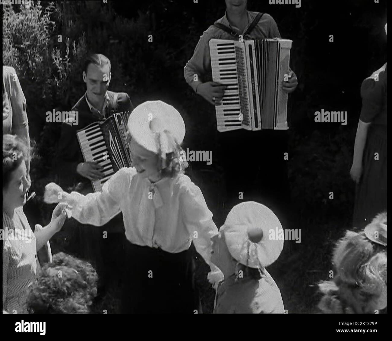 A Group of British Girls Dancing as Two British Men Play accordéon Music, 1938. De "Time to Remember - Wind Up week", 1938 (bobine 1) ; film documentaire sur 1938 - les gens prennent conscience de la menace croissante de la guerre. Banque D'Images