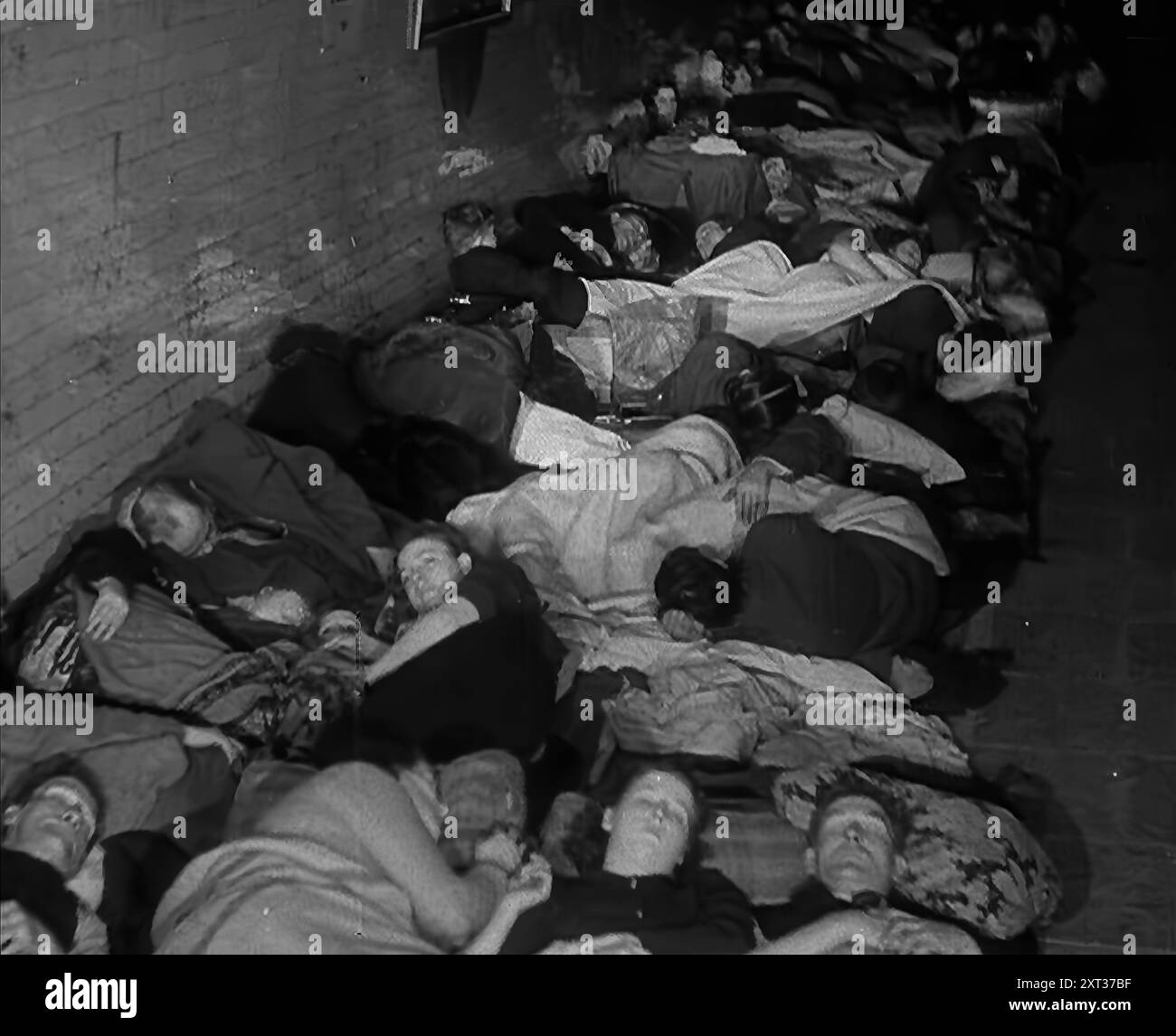 Civils dormant dans le métro londonien, 1940. La Grande-Bretagne pendant la seconde Guerre mondiale : les gens à l'abri du Blitz de Londres. « Au-dessous de la plus grande ville du monde, un hôte s'installe pour dormir, au plus profond de la nuit effrayante [par exemple, les bombardements allemands]. Des terriers pour les êtres humains loin des bombes et une pluie d'acier des armes bien intentionnées [c'est-à-dire britanniques]. De "Time to Remember - Standing Alone", 1940 (bobine 4) ; film documentaire sur les événements des derniers mois de 1940. Banque D'Images