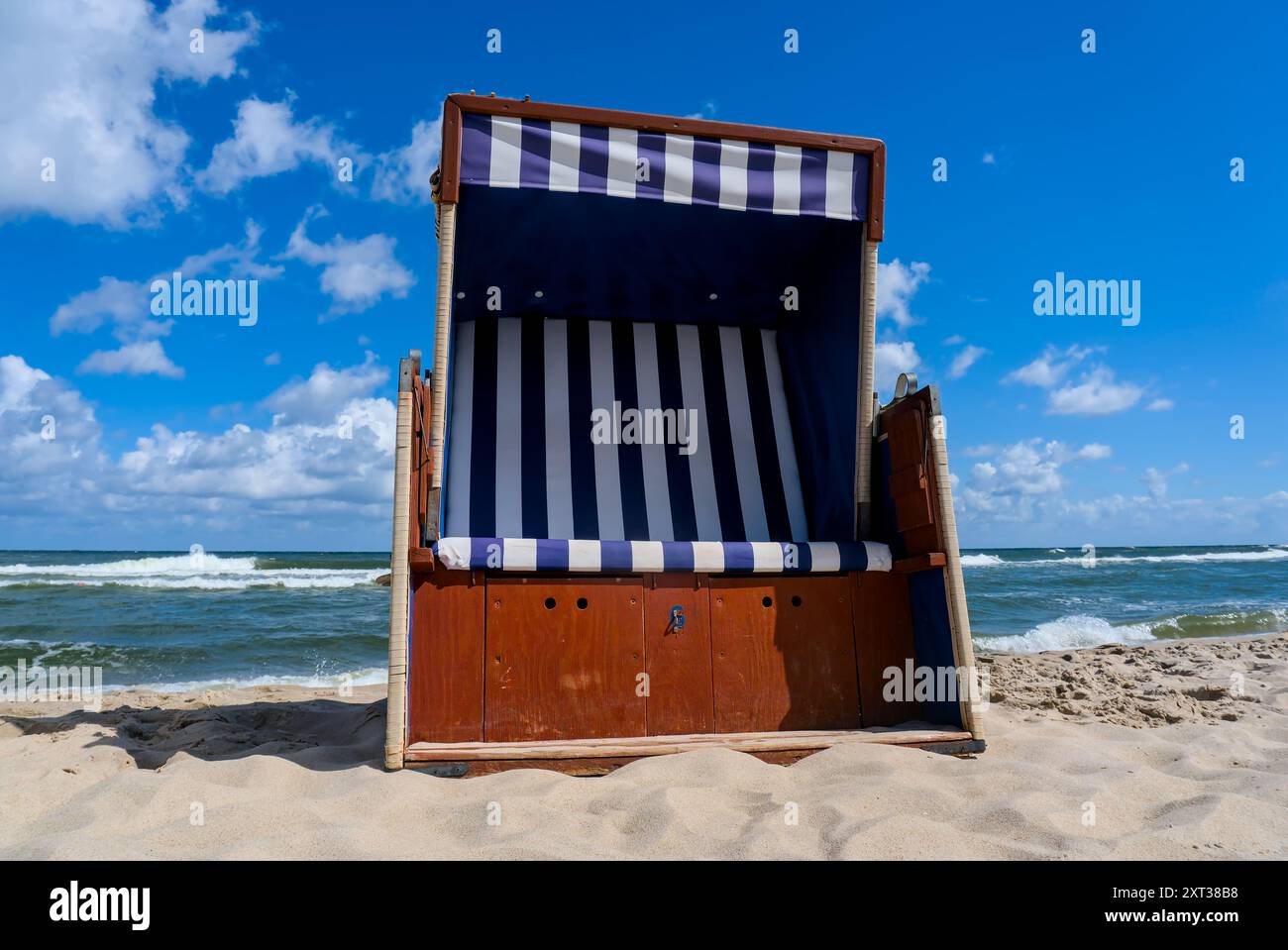 Chaise de panier de plage sur le rivage de sable avec les vagues de la mer Baltique à Jastarnia, Pologne, sous un ciel bleu clair. Banque D'Images